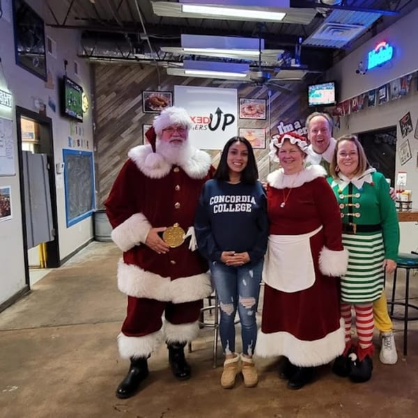 Santa, Mrs. Claus, an elf, and two others pose for a photo inside Mixed Up Burgers.